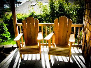 Two wooden chairs on a sunlit porch.