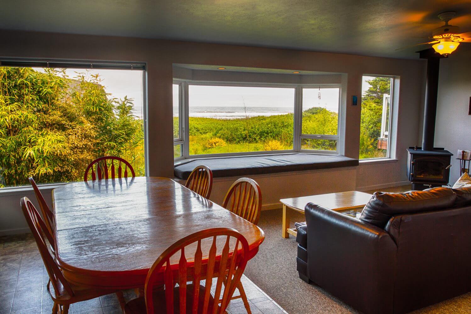 Cozy room with a wooden table and scenic window view of greenery and water.