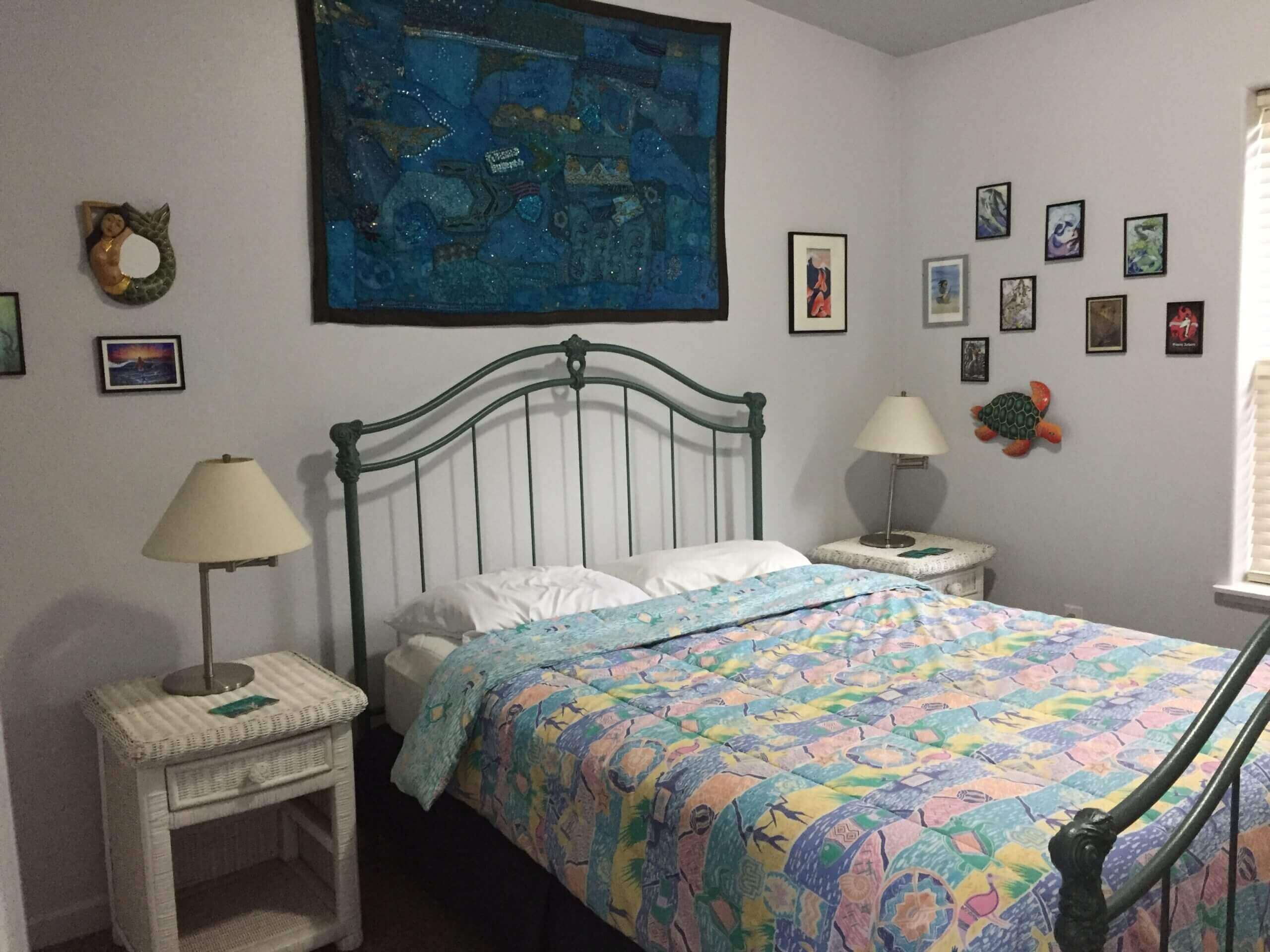 Cozy bedroom with patterned quilt and decorative wall art.
